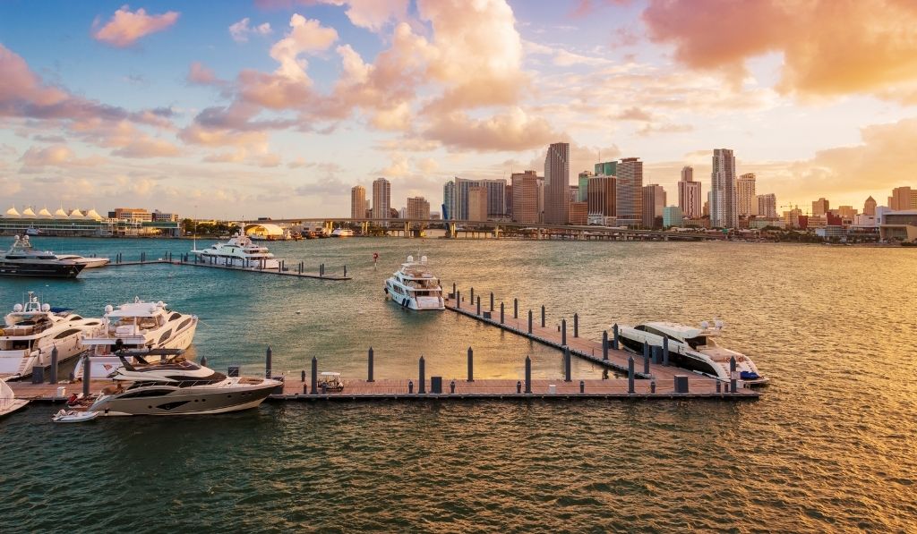 Vista del horizonte de Miami al atardecer, con edificios iluminados y un cielo colorido.