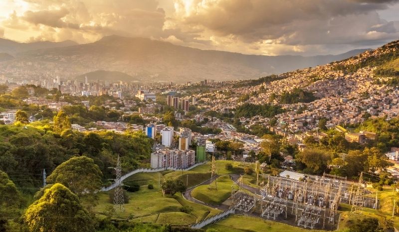 Medellín, atardecer, con cielos naranjas y edificios iluminados, creando un ambiente mágico y acogedor