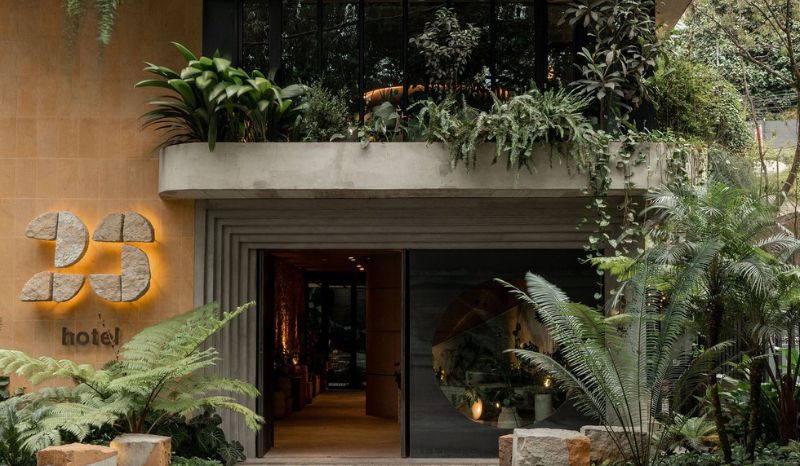 23 Hotel entrance surrounded by lush plants and trees, creating a welcoming and serene atmosphere.
