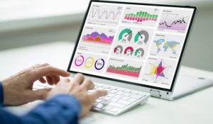 A person working on a laptop displaying various graphs and data visualizations.