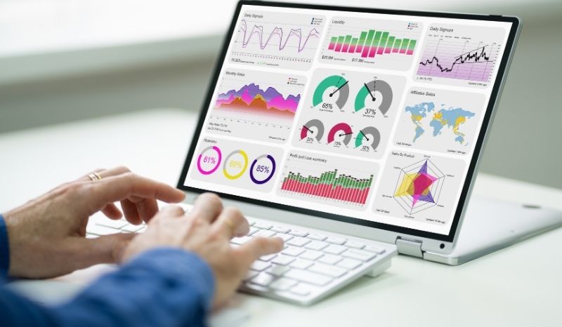 A person working on a laptop displaying various graphs and data visualizations.