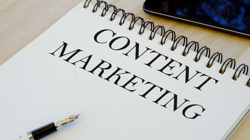 libreta de apuntes con el texto "Content Marketing" junto a una pluma elegante, simbolizando la planificación editorial.