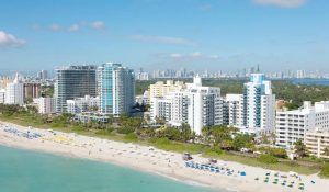 Escena costera de Miami, mostrando la playa y edificios altos en un día soleado.