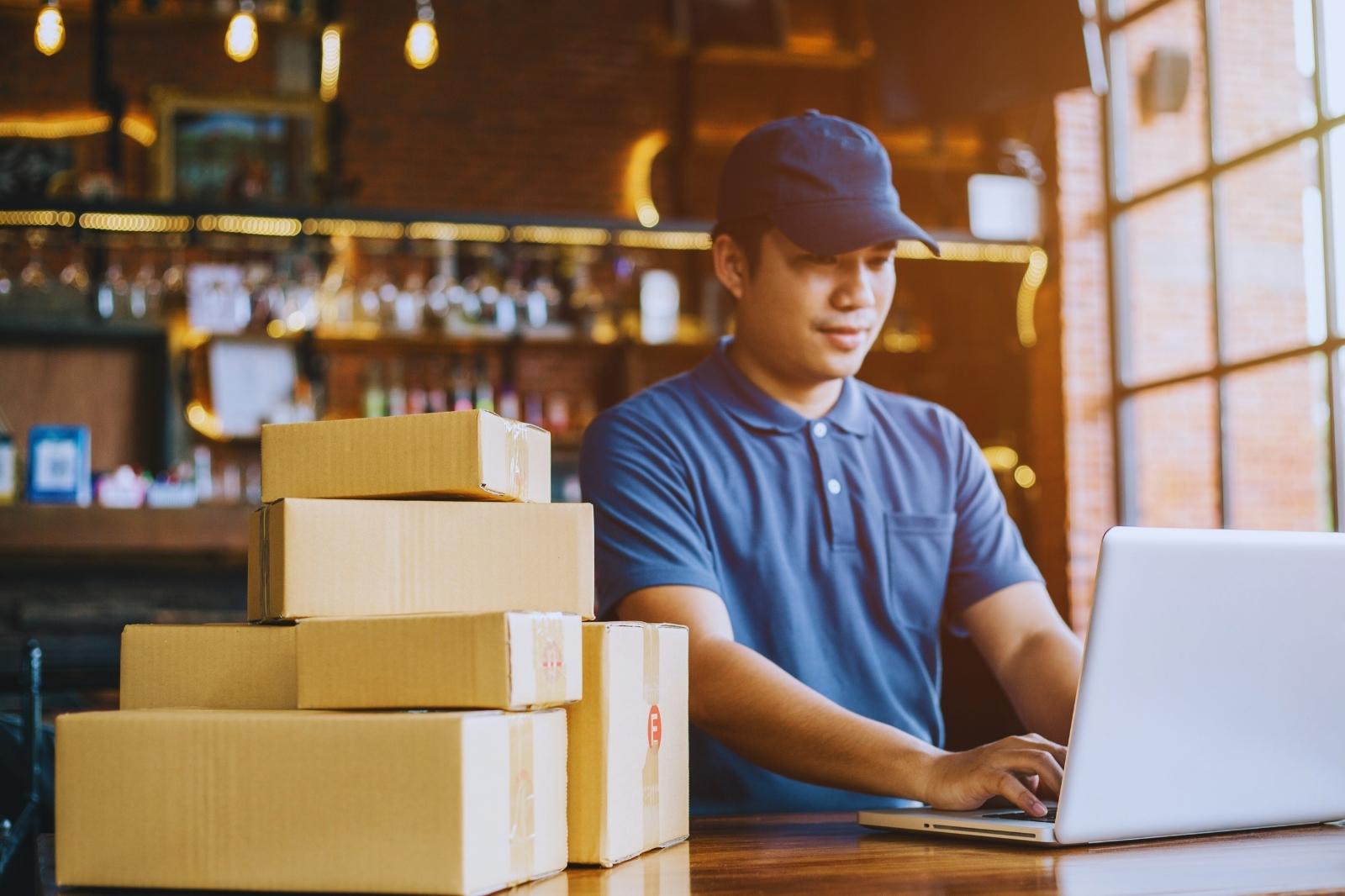 Man focused on his laptop, with boxes stacked around him.