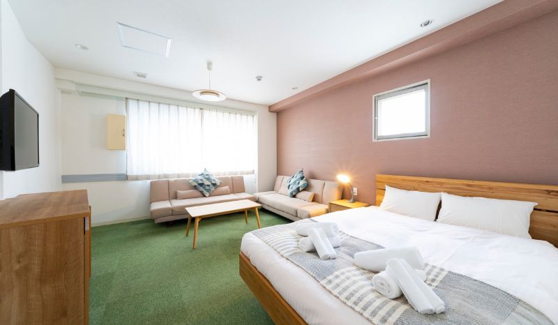 Habitación de hotel con una cama, un sofá y un televisor en un ambiente acogedor y bien iluminado.
