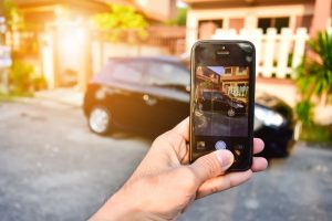 Person holding a cell phone displaying an image of a car.