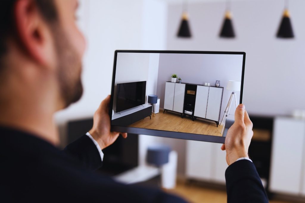 Hombre levantando una tableta con una representación virtual de un salón acogedor.
