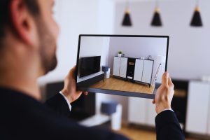 Hombre levantando una tableta con una representación virtual de un salón acogedor.