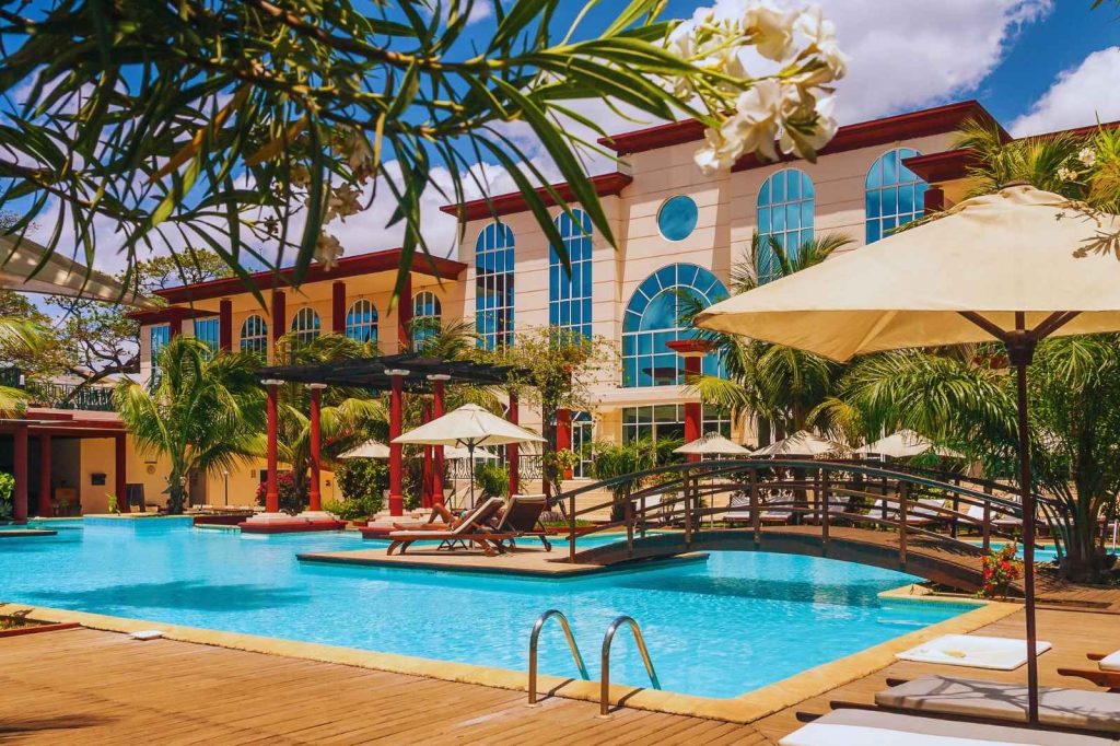 Vista de la piscina del hotel, con áreas de descanso y vegetación tropical alrededor.