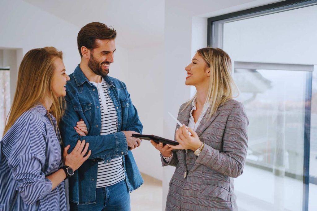 Un agente inmobiliario habla con una pareja y una mujer joven sobre propiedades.