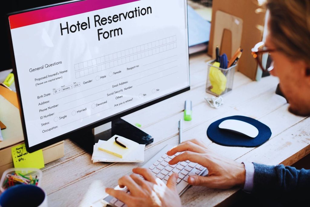 Hombre sentado frente a una computadora, reservando un hotel en línea.