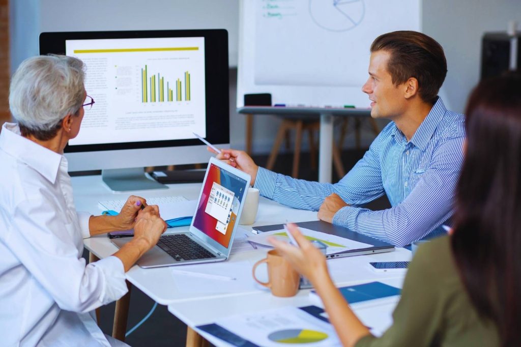 Three people sitting at a table, looking at a computer screen.