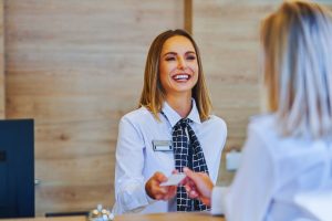 A woman is talking to another woman at the reception desk.
