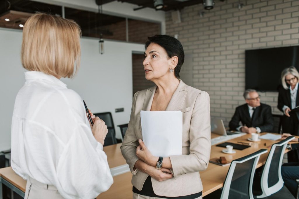 Dos mujeres de negocios conversando en una sala de reuniones