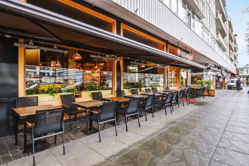 Restaurante con mesas y sillas en la acera