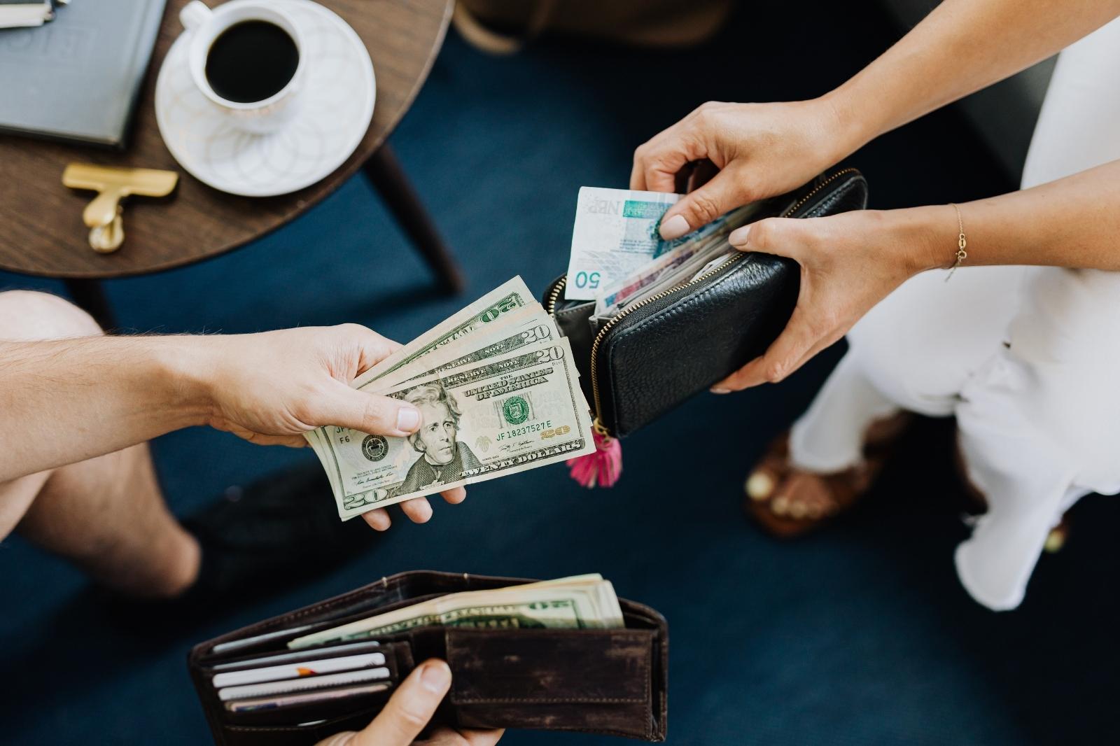 Un hombre entrega dinero a otro que sostiene una billetera, en un contexto de agencia de marketing digital.