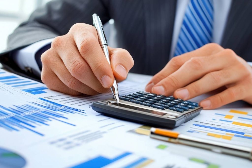 Hombre de traje usando una calculadora y un bolígrafo en un escritorio, trabajando en una agencia de marketing digital.
