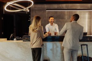 Un hombre y una mujer están de pie en el mostrador de recepción, conversando con el personal.