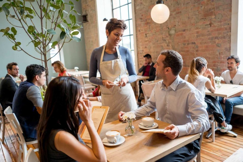 Una camarera sirviendo a los clientes en un restaurante con una sonrisa.