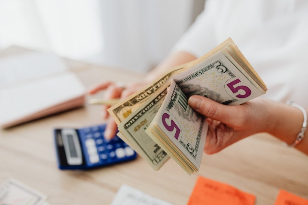 Mujer sosteniendo dinero frente a una calculadora.