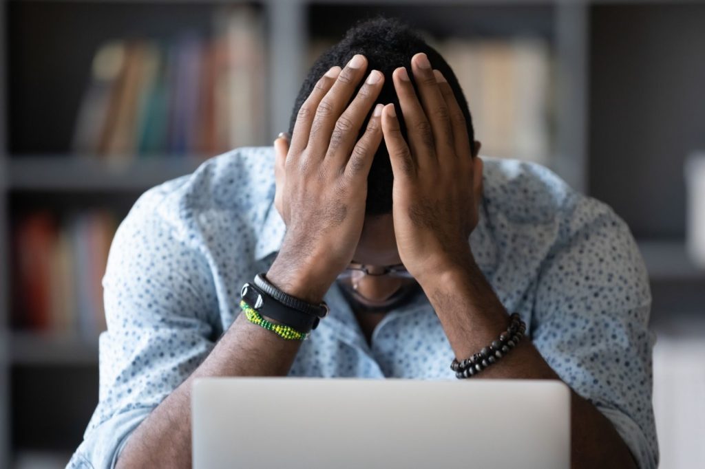 Hombre sentado en un escritorio con las manos en la cabeza.