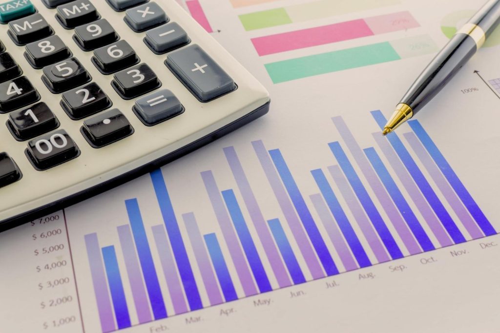 Calculadora, bolígrafo y papel con gráficos.