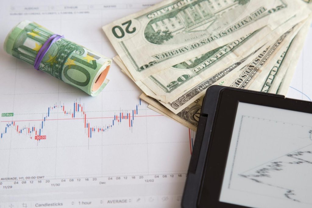 Billetes de dólar y gráficos de acciones sobre un escritorio.