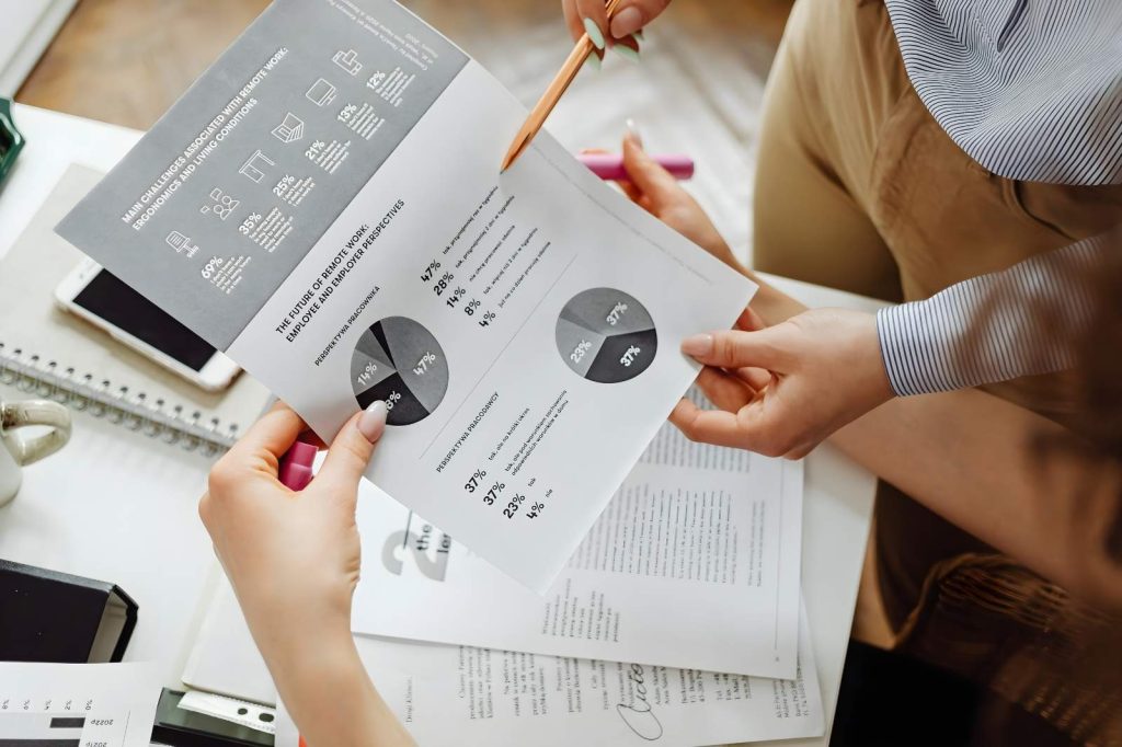 Personas de negocios sosteniendo documentos y un bolígrafo mientras observan gráficos en una reunión.