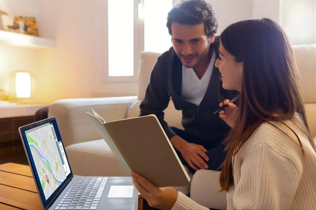 Una pareja mirando un mapa en una computadora portátil.
