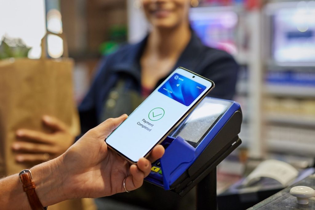 Persona utilizando un teléfono móvil para pagar un producto en una tienda.