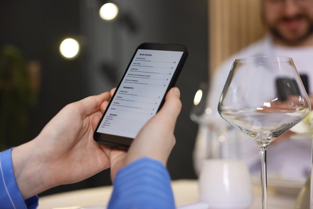 Persona sosteniendo un smartphone que muestra un menú en la pantalla.