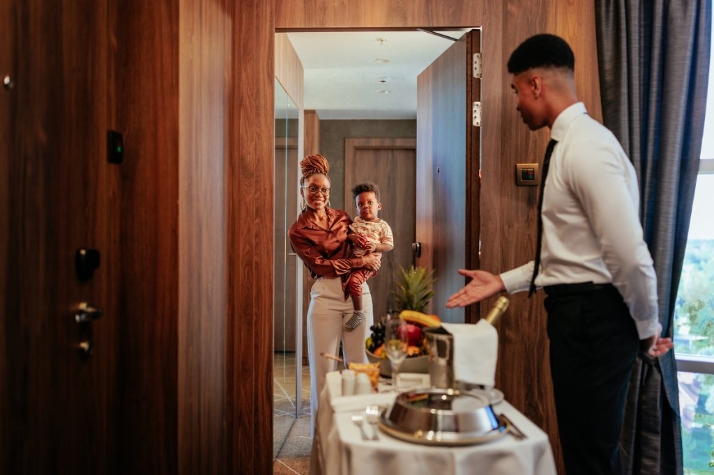 Empleado de hotel entregando catering y frutas a huéspedes en la habitación.