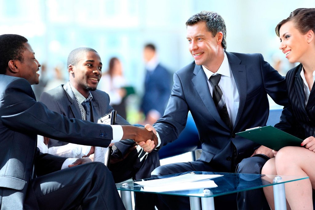 Equipo de trabajo diverso celebrando un acuerdo con un apretón de manos después de una capacitación en storytelling corporativo.