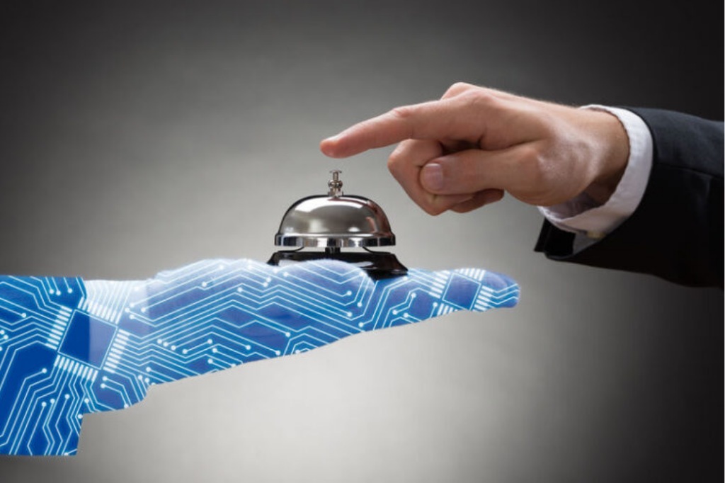 Mano humana pulsando una campana de recepción sostenida por una mano digital con circuitos integrados.