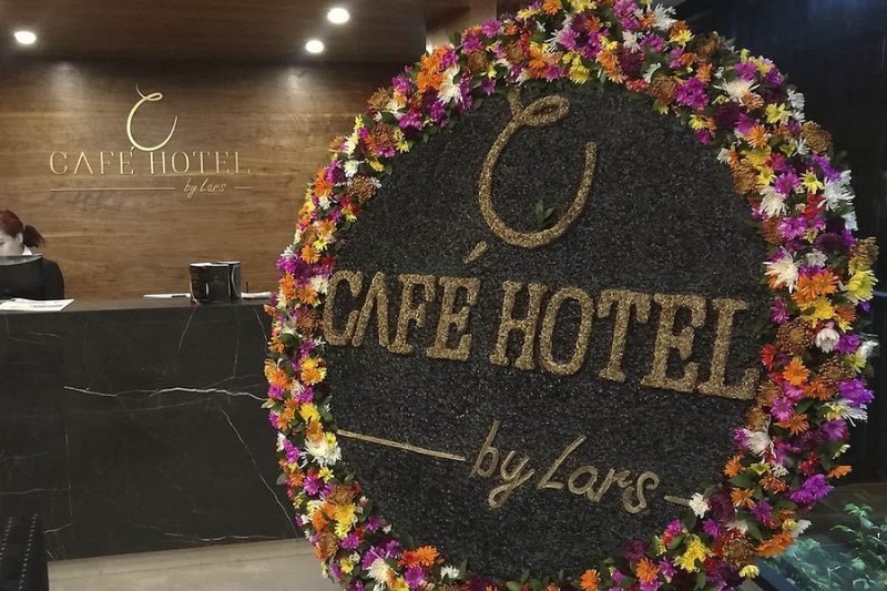Recepción del Café Hotel en Medellín con logo decorado con flores naturales coloridas.