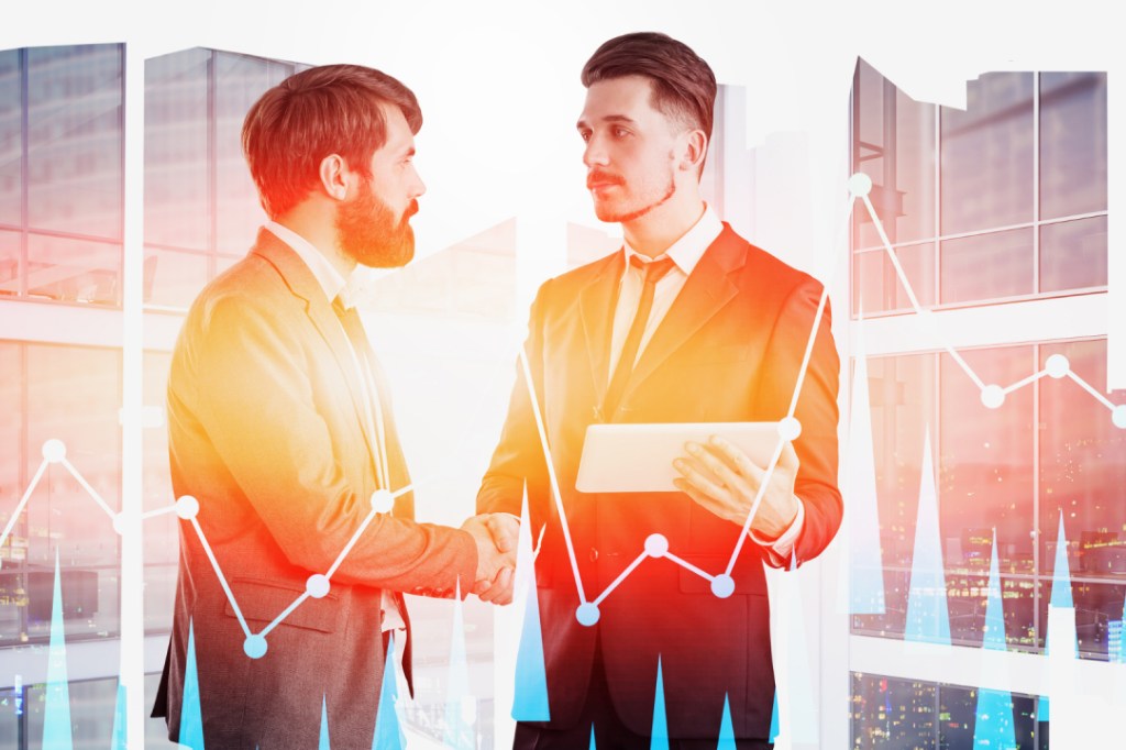 Dos consultores de una agencia growth partner en Colombia estrechando la mano frente a una gráfica de crecimiento