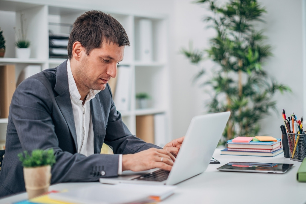 Profesional analizando opciones en laptop, representando preguntas clave de clientes B2B al buscar sedes para eventos corporativos.