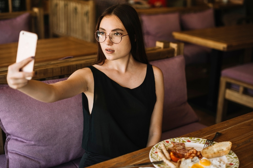 Cliente tomando foto de su comida en restaurante, creando contenido auténtico e instagrammable sin parecer publicidad directa.