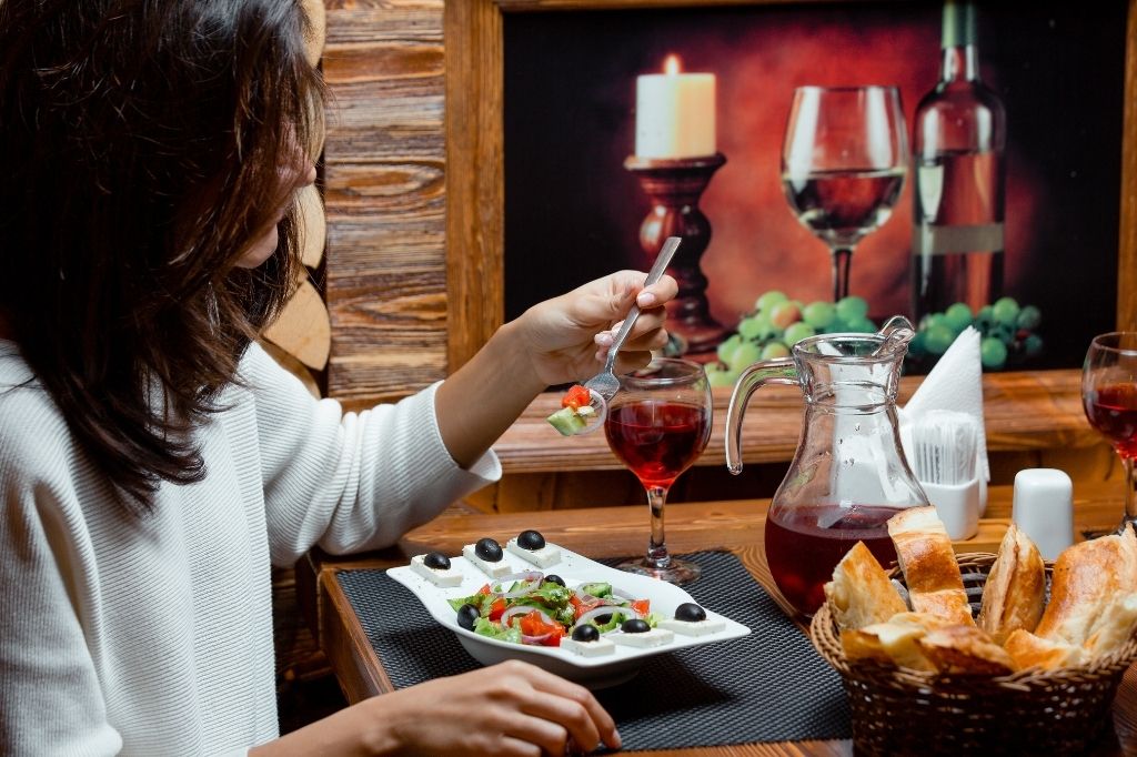 Cliente disfrutando plato y vino en restaurante, creando contenido gastronómico atractivo e instagrammable sin enfoque publicitario.