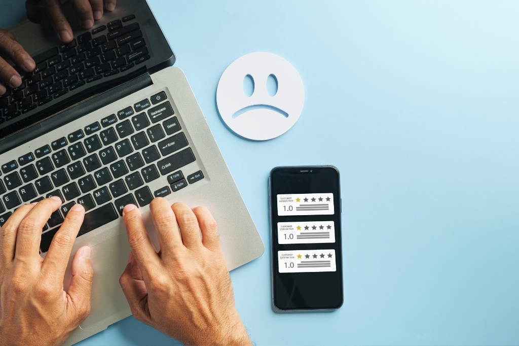 Gestión de reseñas negativas en smartphone y laptop, representando protocolo de crisis digital y reputación online en restaurante de lujo.