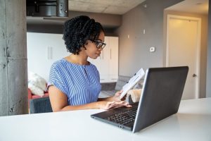 Profesional analizando datos en laptop con documentos, representando uso de CRM con IA para personalizar oferta inmobiliaria en Miami.