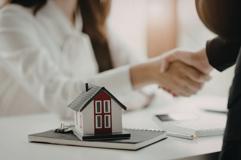 Acuerdo inmobiliario con apretón de manos y maqueta de casa, representando uso de CRM con IA para personalizar ofertas en Miami.