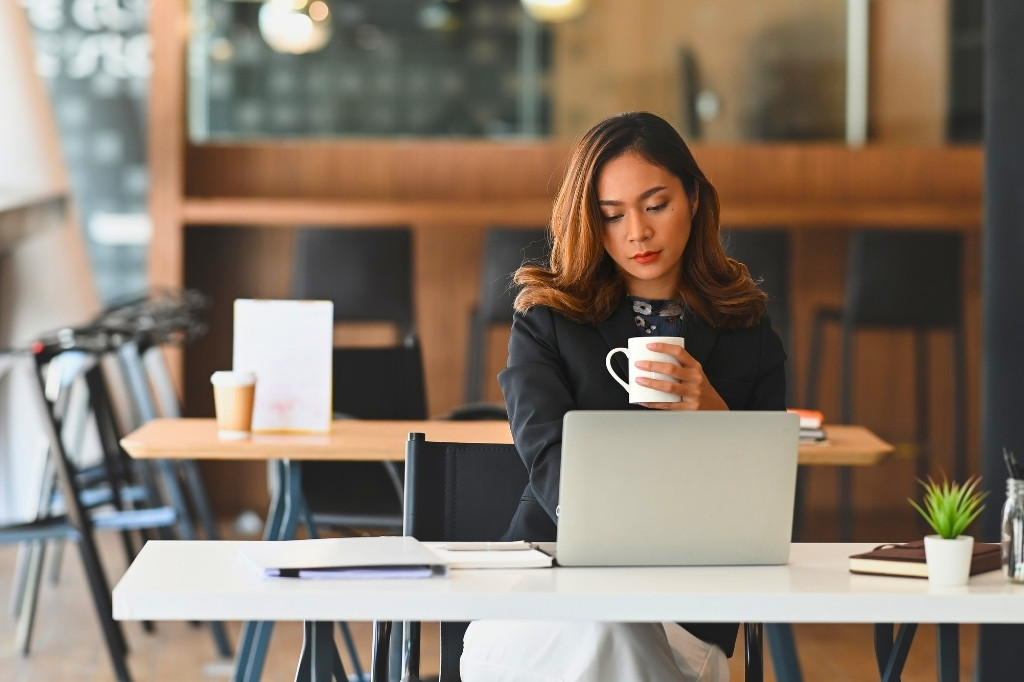 Nómada digital trabajando con laptop en cafetería, valorando comodidad, conectividad y espacios tranquilos en hotel de Medellín.