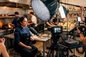Grabación de entrevista a una chef profesional con equipo de video cinematográfico e iluminación Aputure en una cocina industrial.