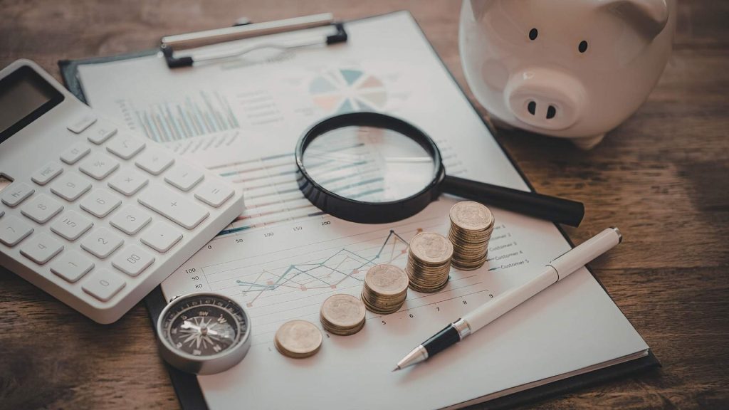 Reporte financiero con monedas en escala ascendente, calculadora y brújula.