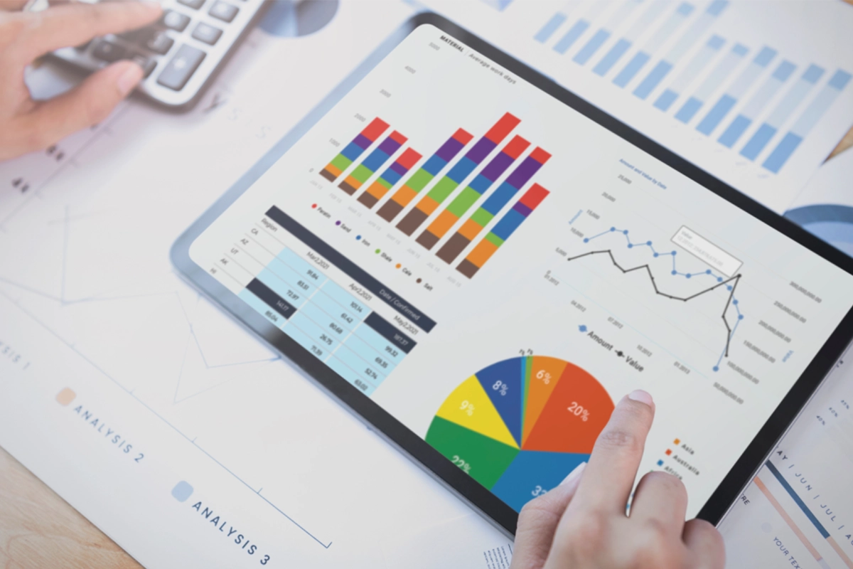 Analista revisando dashboard de analítica de datos con gráficas de barras, torta y líneas en tablet.